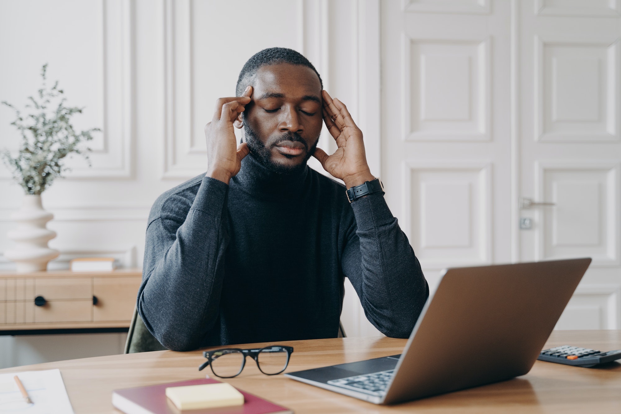 Frustrated tired afro american man office worker with closed eyes trying to concentrate at workplace